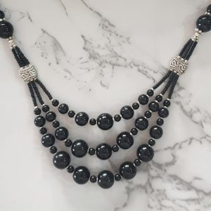 Shimmering Spheres - Handmade Kalasha Necklace The Shimmering Sphere necklace is just the right accessory to create a bold and striking fashion look. This handmade Kalasha necklace reflects light to give it a dazzling glow, perfect to make you look radiant and beautiful. Colour: Black Stone: Aqeeq