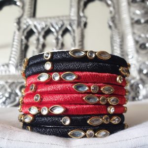 Black & Red - Silk Thread Kundan Bangles Exquisite bangles wrapped in graceful diaphanous silk thread topped with dazzling Kundan embellishments. Handcrafted and designed to perfection, these bangles are lightweight, eye-catching, and the definition of elegance. Perfect for all occasions, be it an outing, a party, or a wedding, these bangles will always enhance and add to your look!