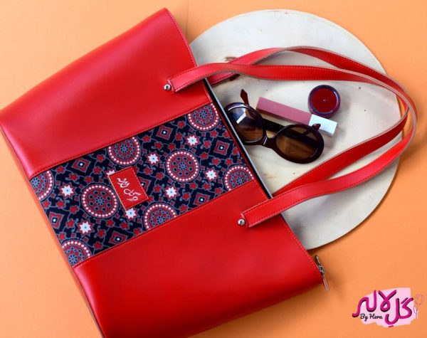 Vibrant Red - Faux Leather Tote Bag A classical handbag with a traditional twist. Featuring a simple & popular silhouette, this bag is perfect to carry everything you need to have with you when on the go! Made out of faux leather with traditional printed fabric incorporated to make it stand out and give it a desi touch! Colour: Red Size Length: 17 inches Width: 4.5 inches Depth: 10.5 inches