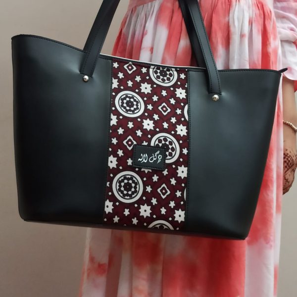 Mystical Black - Faux Leather Tote Bag A classical handbag with a traditional twist. Featuring a simple & popular silhouette, this bag is perfect to carry everything you need to have with you when on the go! Made out of faux leather with traditional printed fabric incorporated to make it stand out and give it a desi touch!