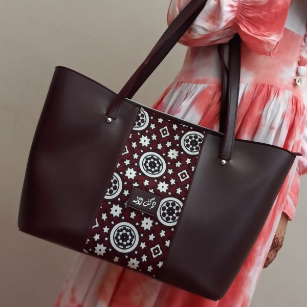 Burgundy Vibes - Faux Leather Tote Bag A classical handbag with a traditional twist. Featuring a simple & popular silhouette, this bag is perfect to carry everything you need to have with you when on the go! Made out of faux leather with traditional printed fabric incorporated to make it stand out and give it a desi touch!