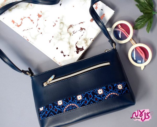 Blue Bliss - Faux Leather Cross-Body Bag A classical cross-body bag with a traditional twist. Featuring a simple & popular silhouette, this bag is perfect to carry everything you need to have with you when on the go! Made out of faux leather with traditional printed fabric incorporated to make it stand out and give it a desi touch!