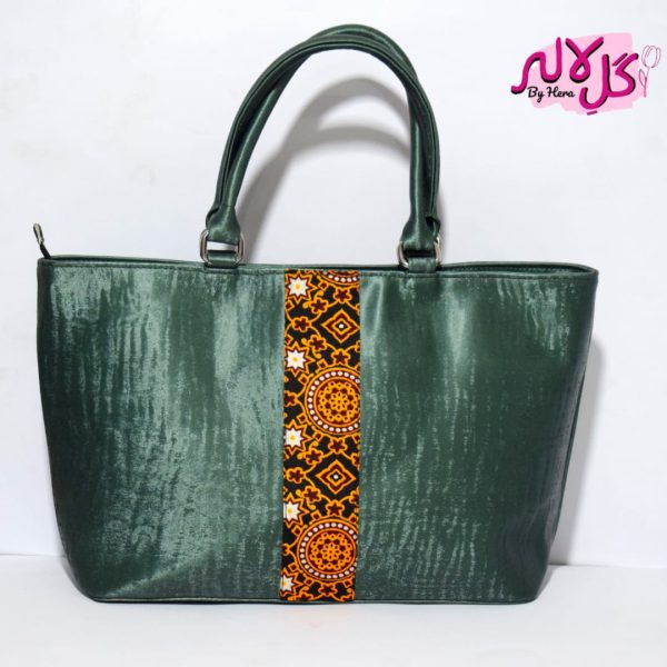 The Sheen Green - Faux Leather Hand Bag A shiny beautiful handbag with a traditional twist. Featuring a simple & popular silhouette, this bag is perfect to carry everything you need to have with you when on the go! Made out of faux leather with traditional printed fabric incorporated to make it stand out and give it a desi touch! Colour: Green