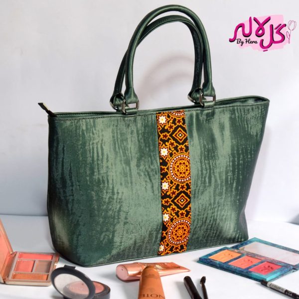 The Sheen Green - Faux Leather Hand Bag A shiny beautiful handbag with a traditional twist. Featuring a simple & popular silhouette, this bag is perfect to carry everything you need to have with you when on the go! Made out of faux leather with traditional printed fabric incorporated to make it stand out and give it a desi touch! Colour: Green