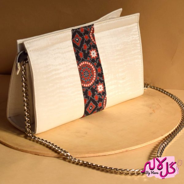 Snow White - Faux Leather Chain Bag A shiny beautiful handbag with a traditional twist. Featuring a simple & popular silhouette, this bag is perfect to carry everything you need to have with you when on the go! Made out of faux leather with traditional printed fabric incorporated to make it stand out and give it a desi touch!